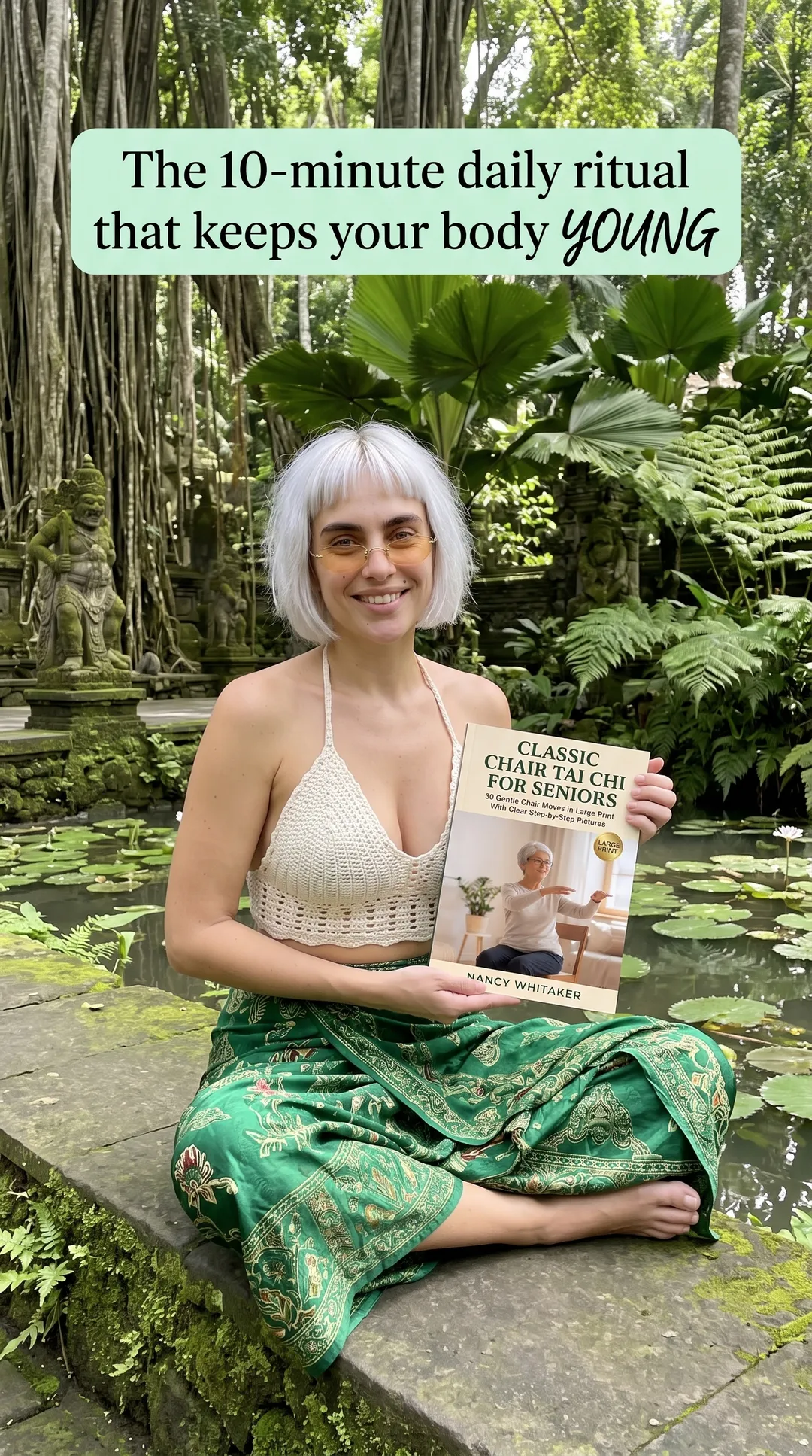 Kaia in a crochet top and green skirt sitting by a lily pond holding Classic Chair Tai Chi for Seniors