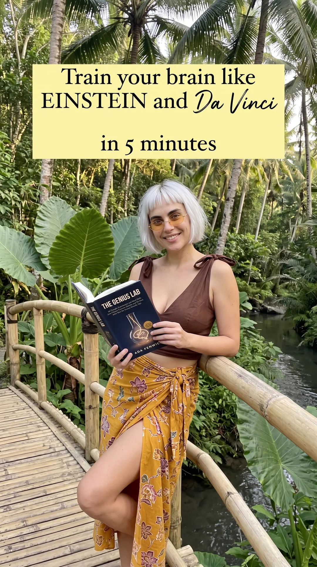 Kaia in a brown top and mustard sarong on a bamboo bridge holding The Genius Lab